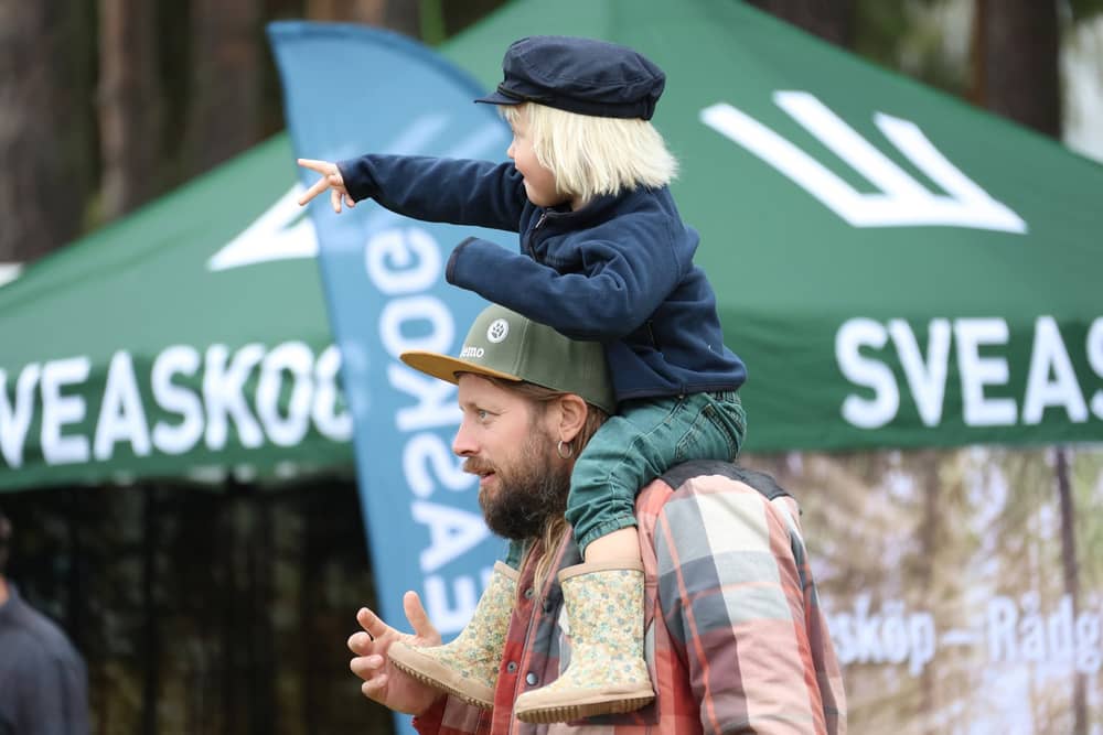 Barn på pappas axlar pekar ut mot mässområdet