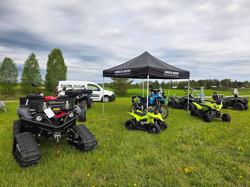 Fyrhjulingar och motorcykel utställda under tält